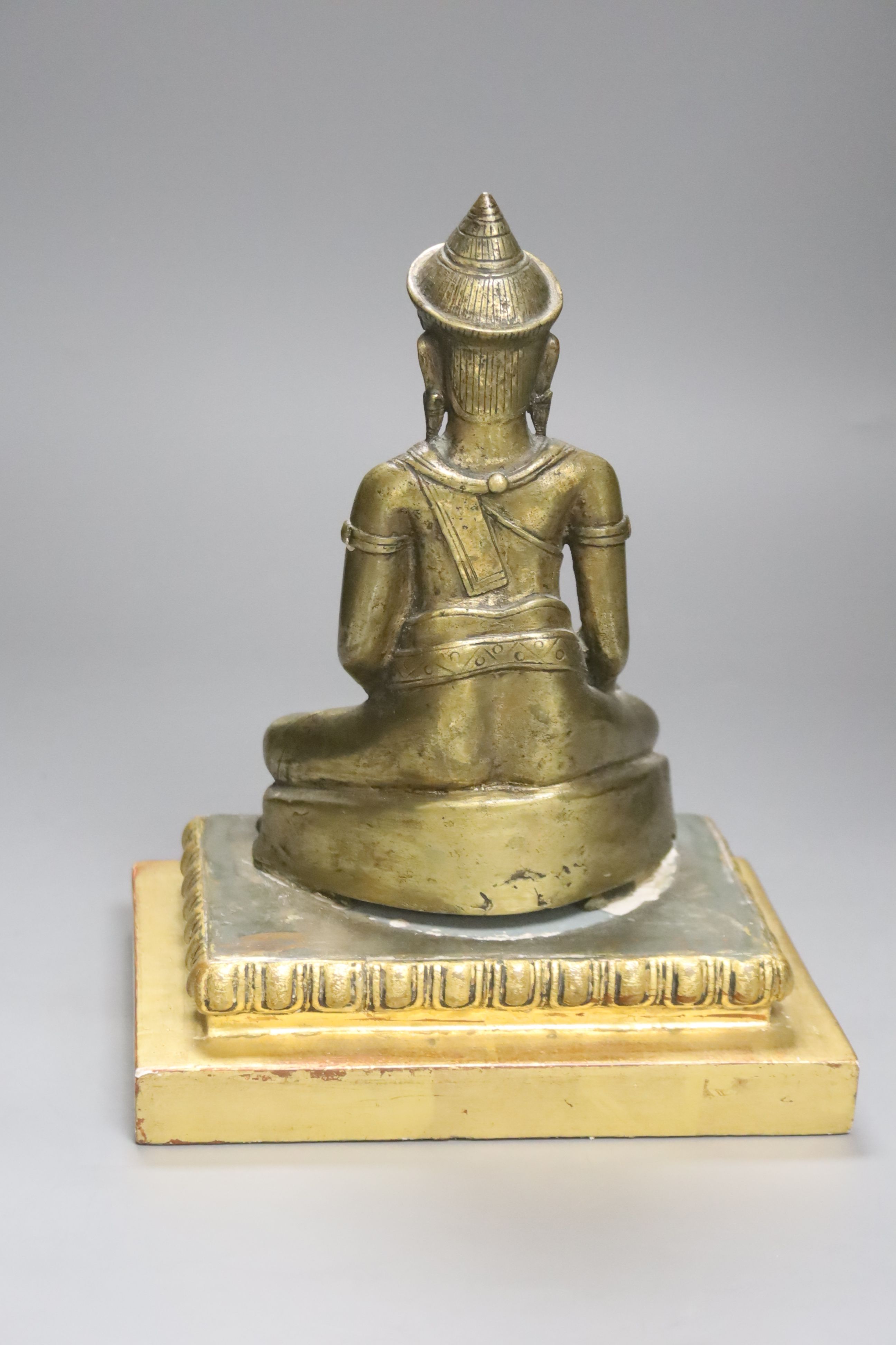 A South East Asian engraved and polished bronze figure of a seated deity, H 19.5cm